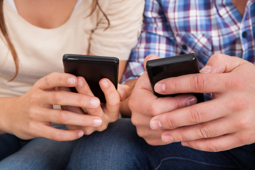 Couple sitting together using their cellphones to text